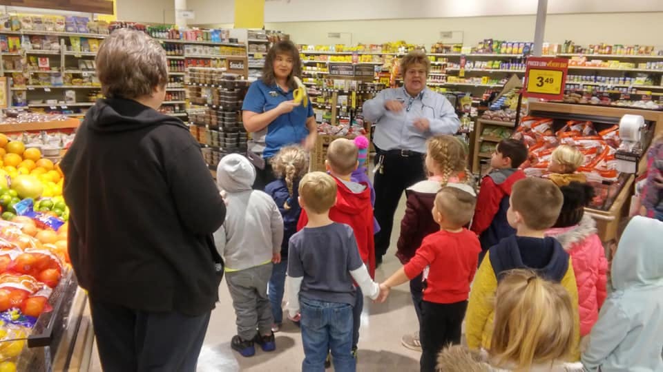 Adults and children gathered in a grocery store aisle