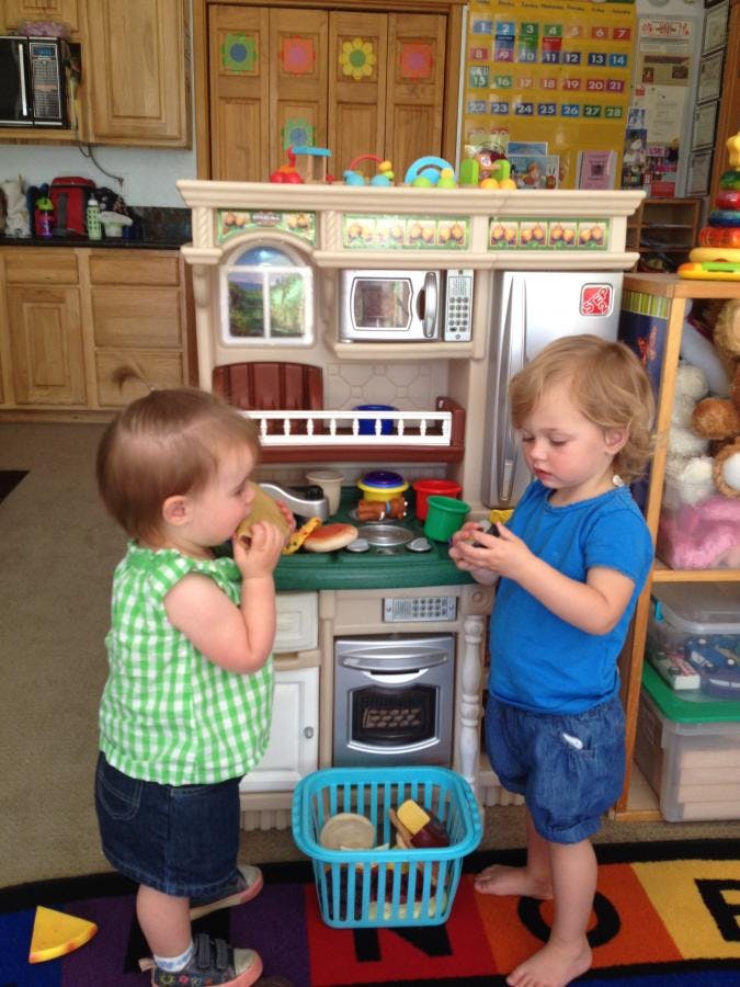 Two children playing with a toy kitchen set