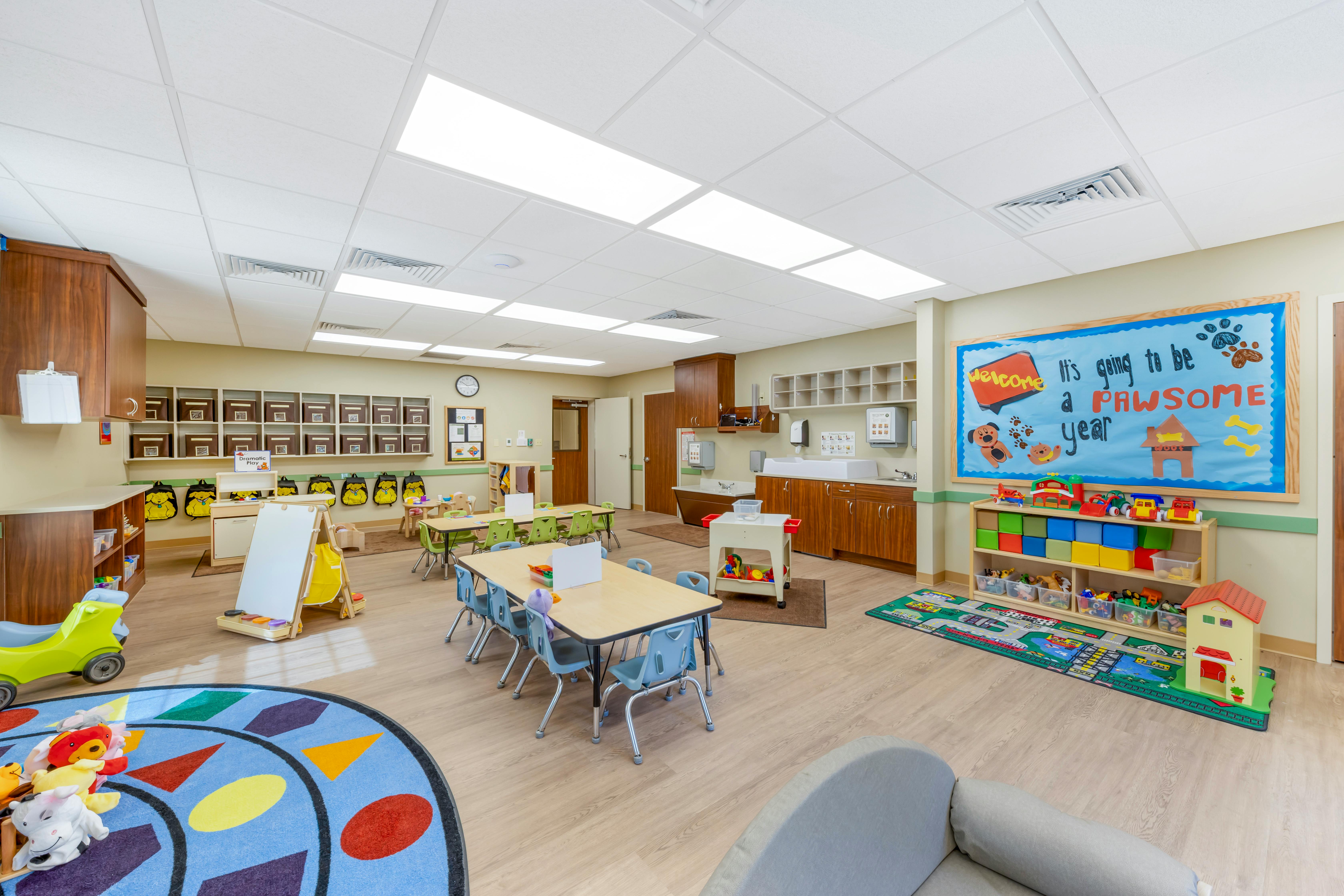 Classroom with child-sized tables and chairs, shelves, and a bulletin board