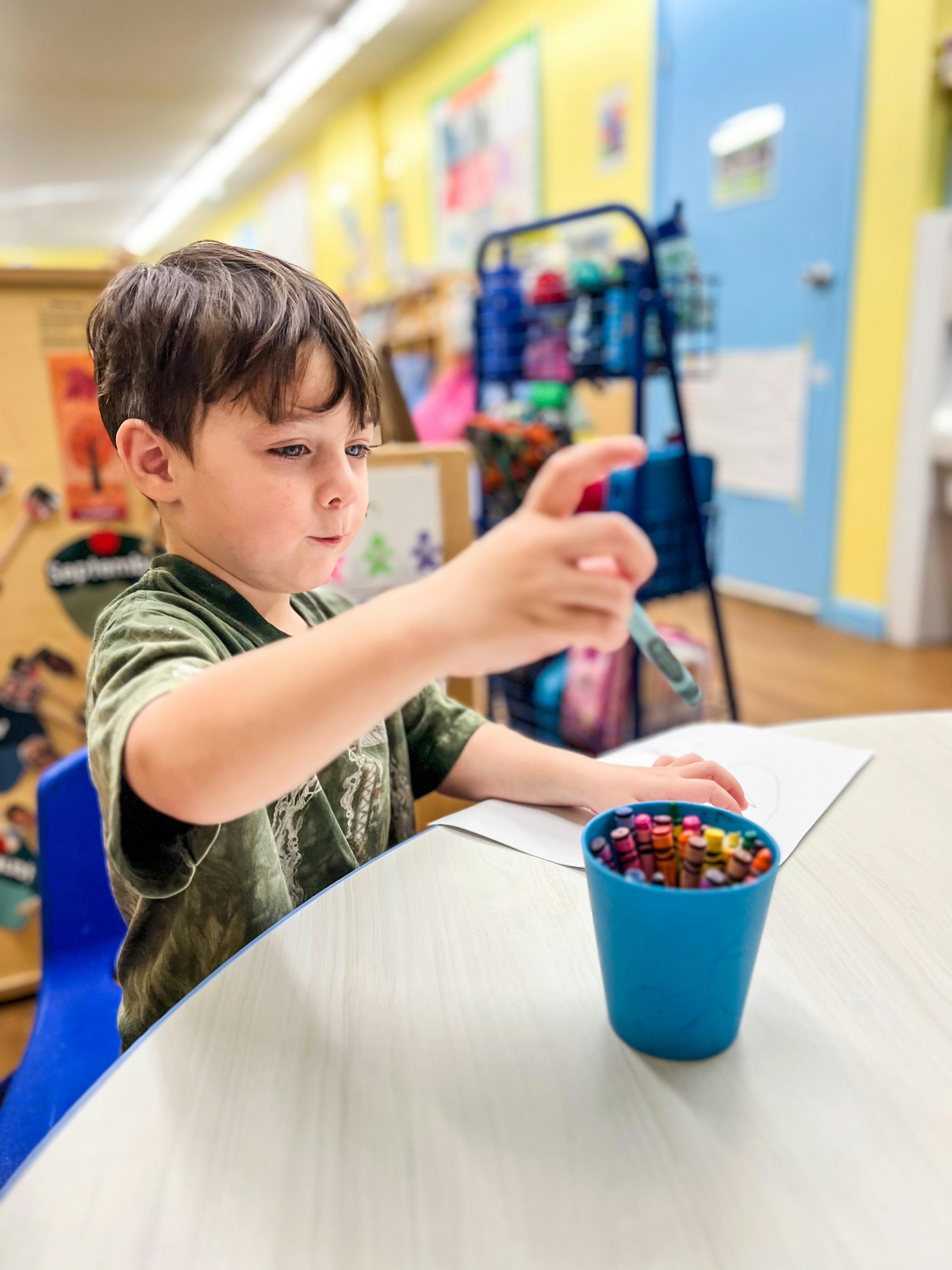 Child drawing at a table in a classroom