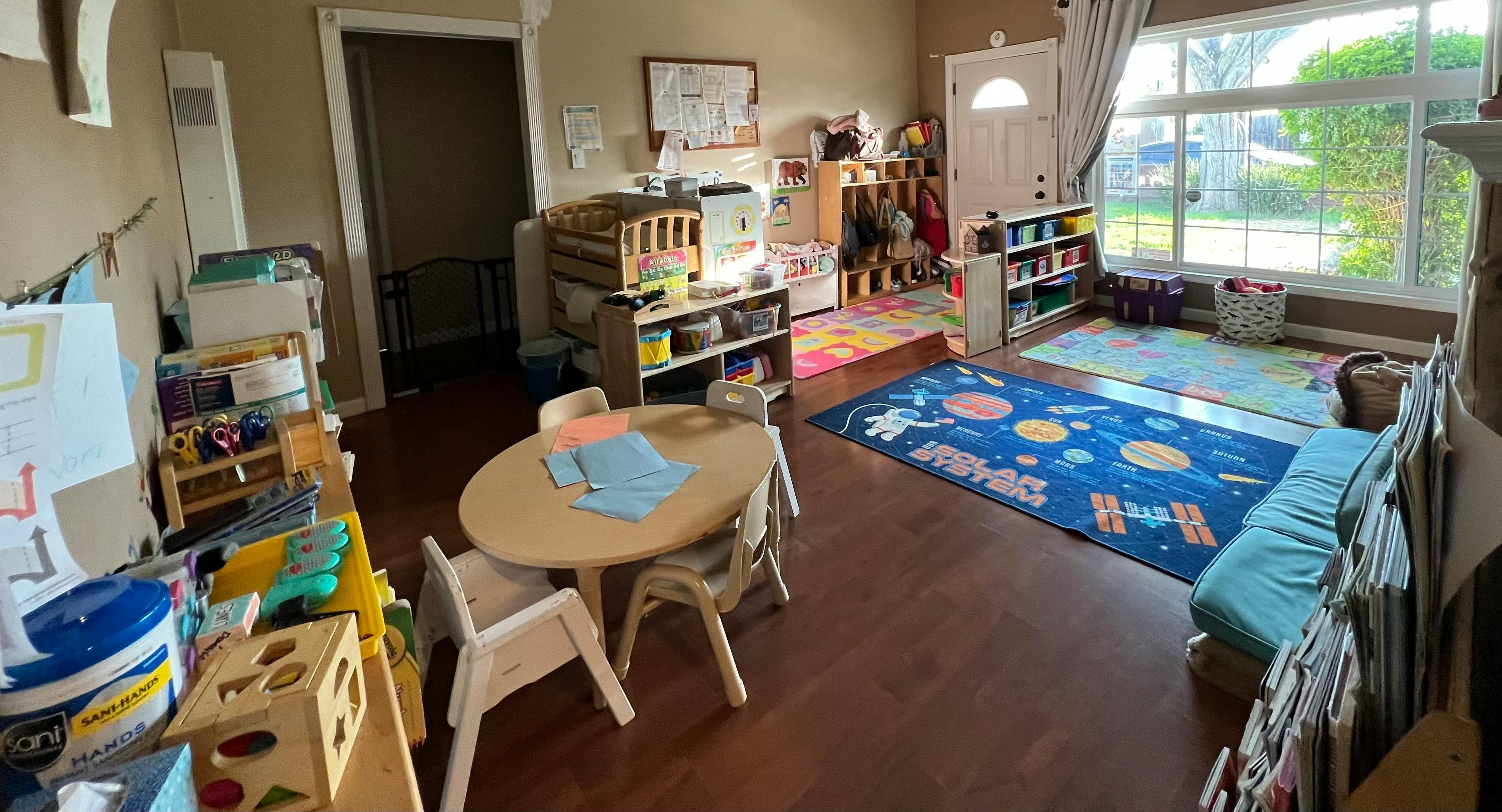 Playroom with small table and chairs, shelves with toys, and a space-themed rug