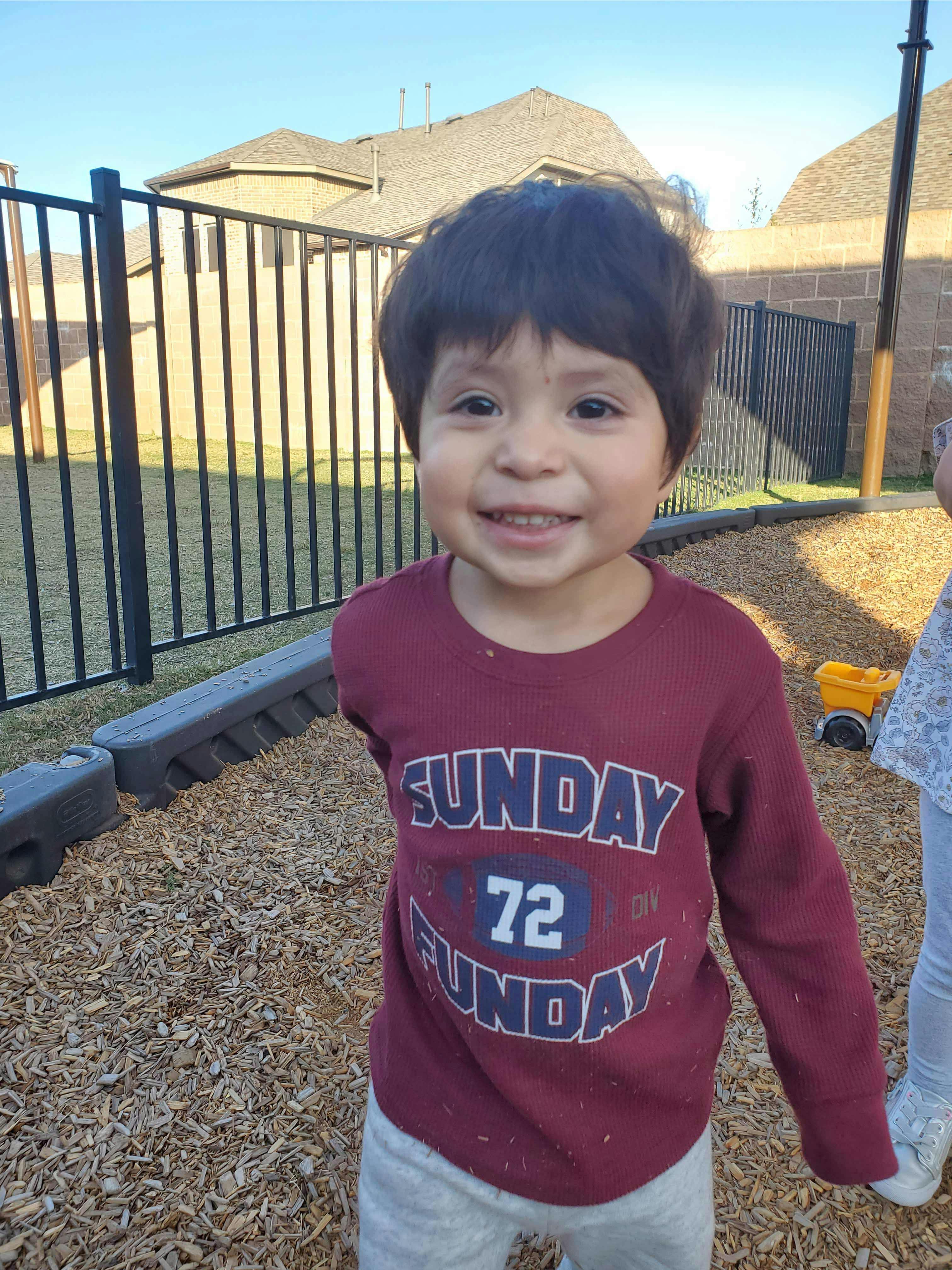 Child in a maroon shirt with "SUNDAY FUNDAY 72" text