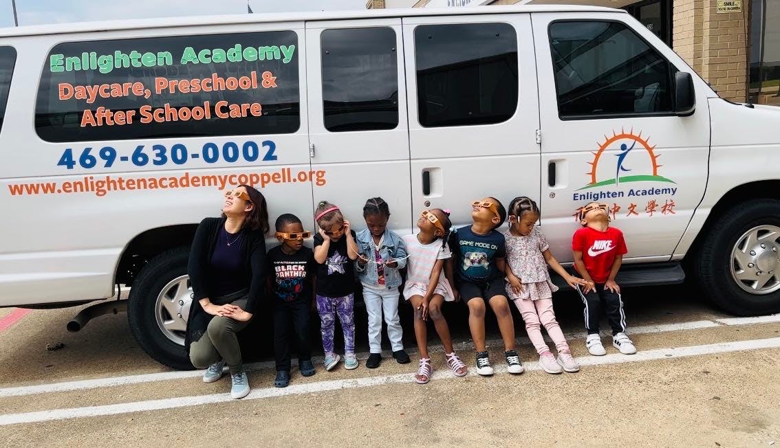 Adult and children sitting in front of a white van with text on its side