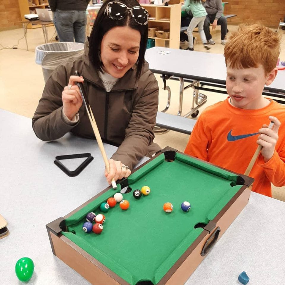 Person and child playing miniature pool