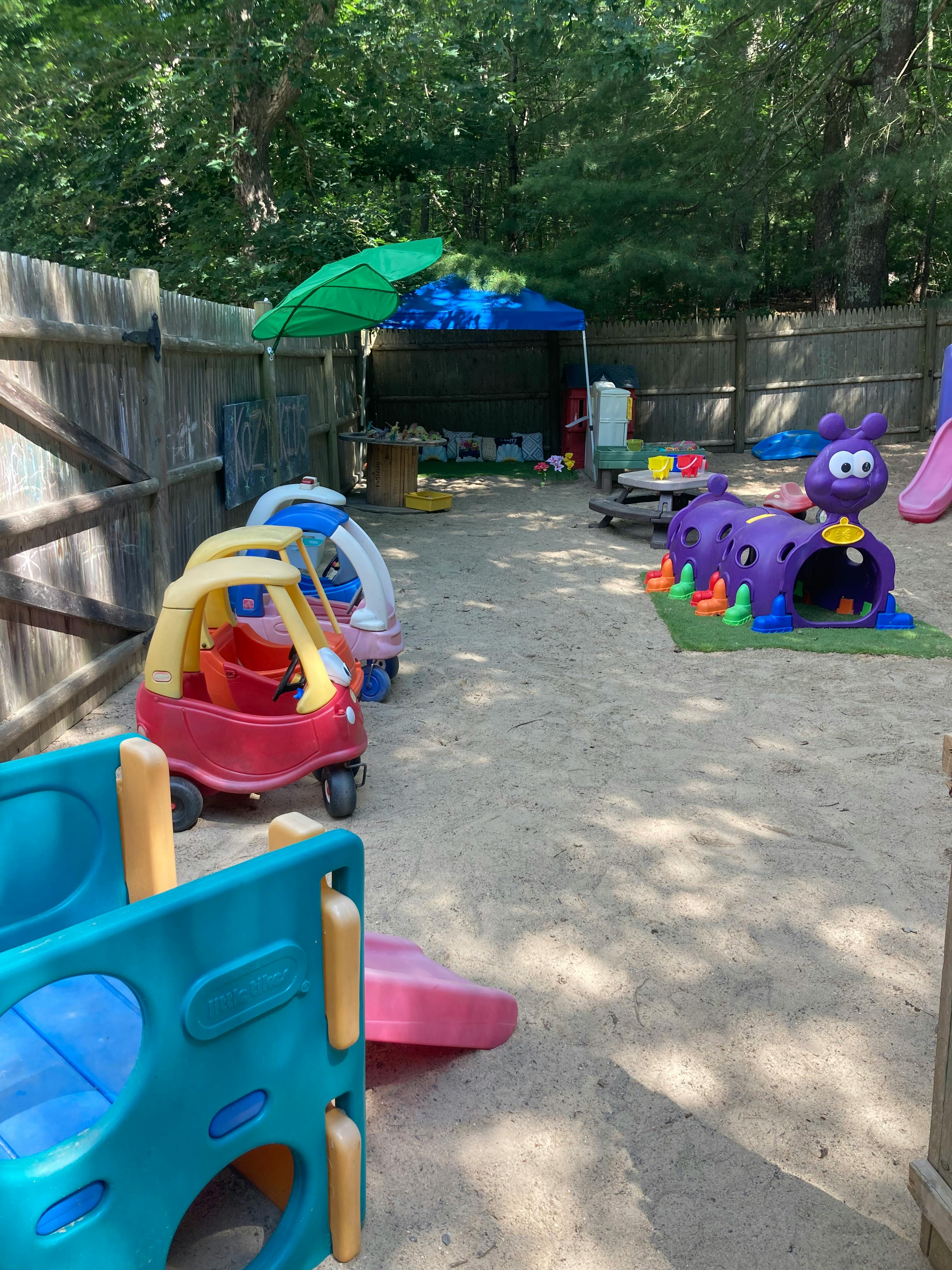 Outdoor playground with toy cars, a purple caterpillar tunnel, and a slide