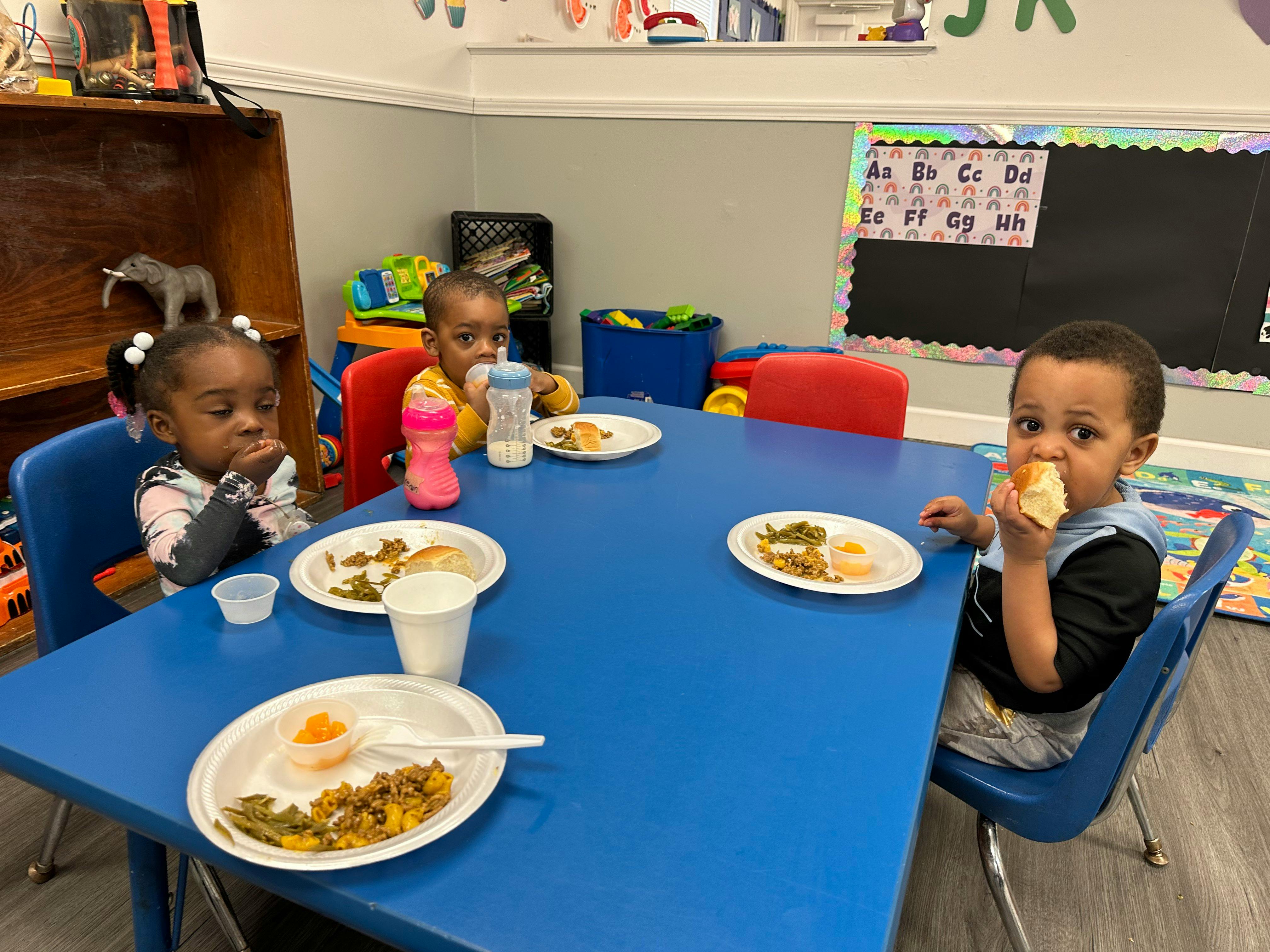 Three children eating at a blue table
