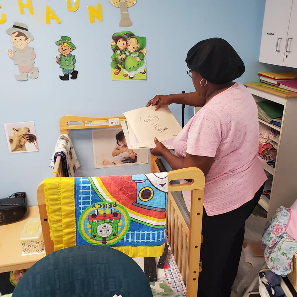 Person holding papers over a crib in a room with wall decorations
