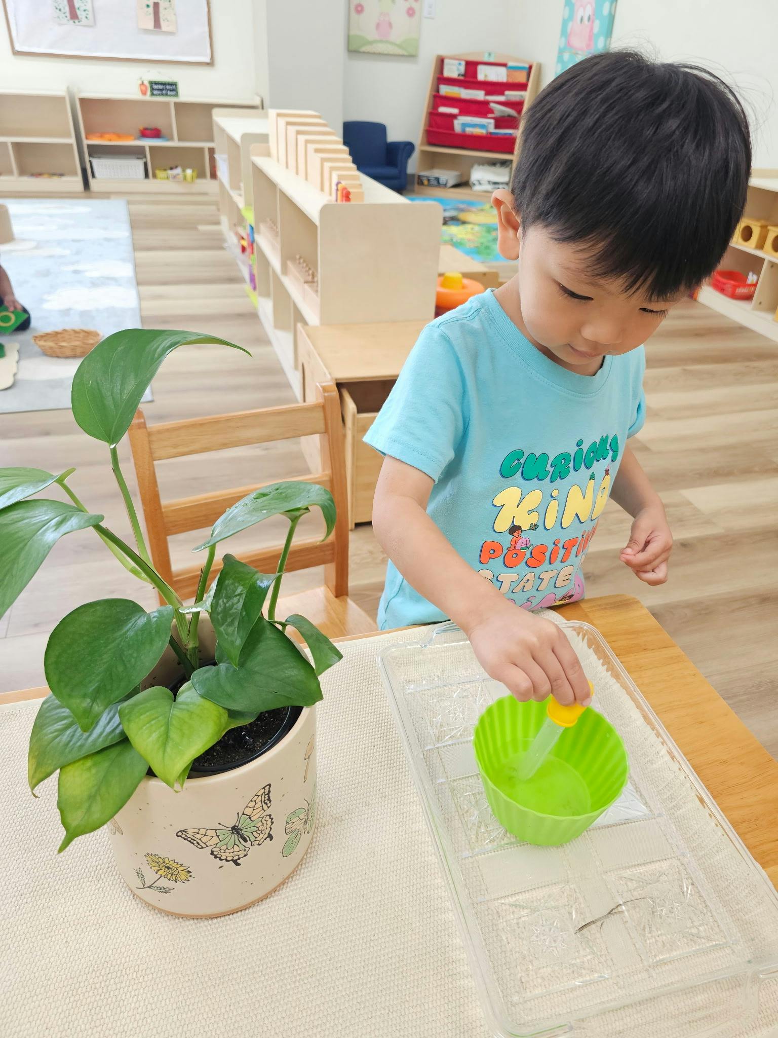 Child using a dropper to transfer water into a green cup