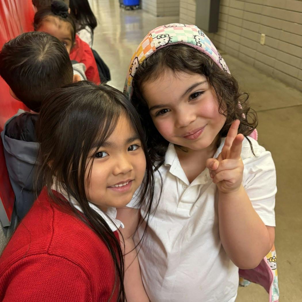 Two children smiling, one holding up a peace sign