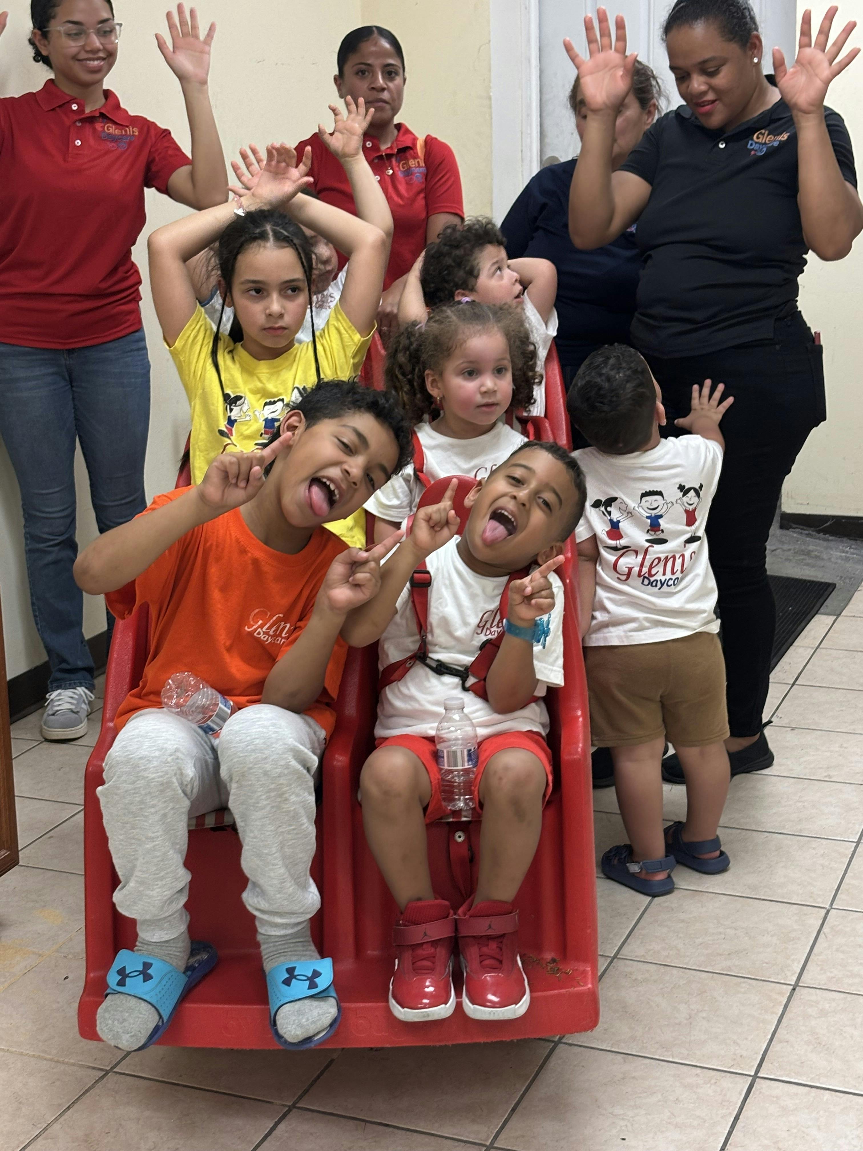 Children and adults raising hands, two children in front making silly faces