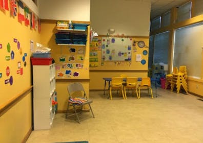 Classroom with yellow walls, small tables and chairs, and a whiteboard