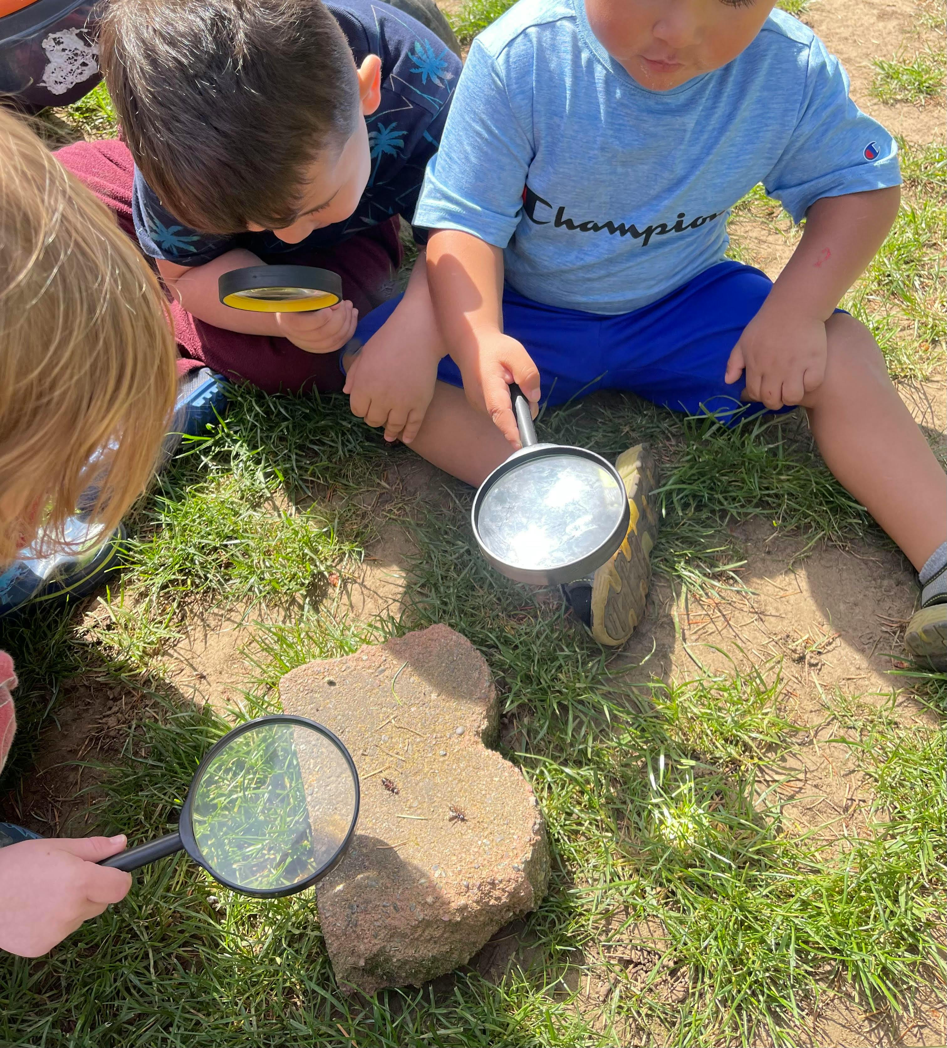 Children using magnifying glasses to look at a rock