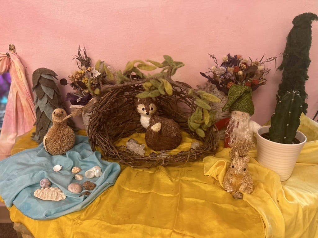 Tabletop display with animal figurines, a nest, and a potted cactus