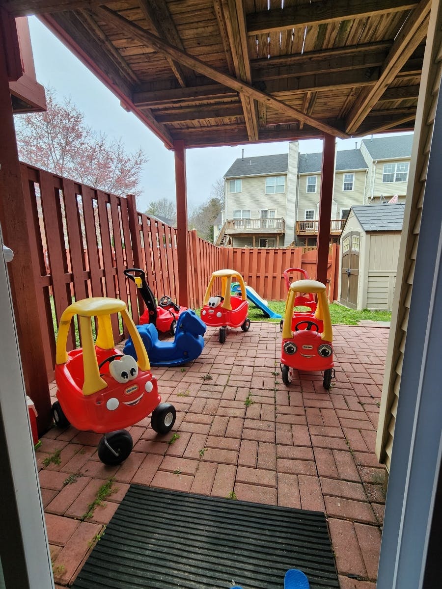Multiple toy cars and a blue rocking horse on a brick patio