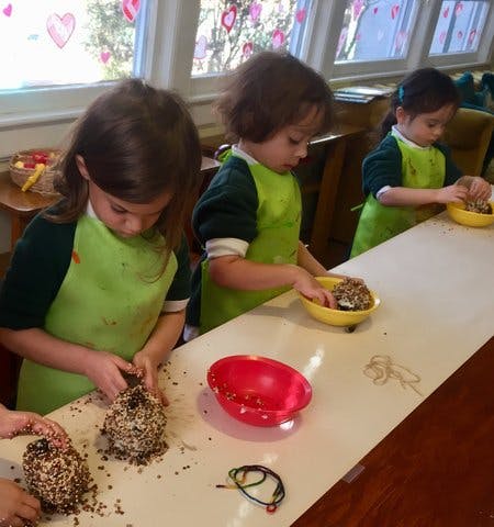 Three children in aprons making crafts at a table
