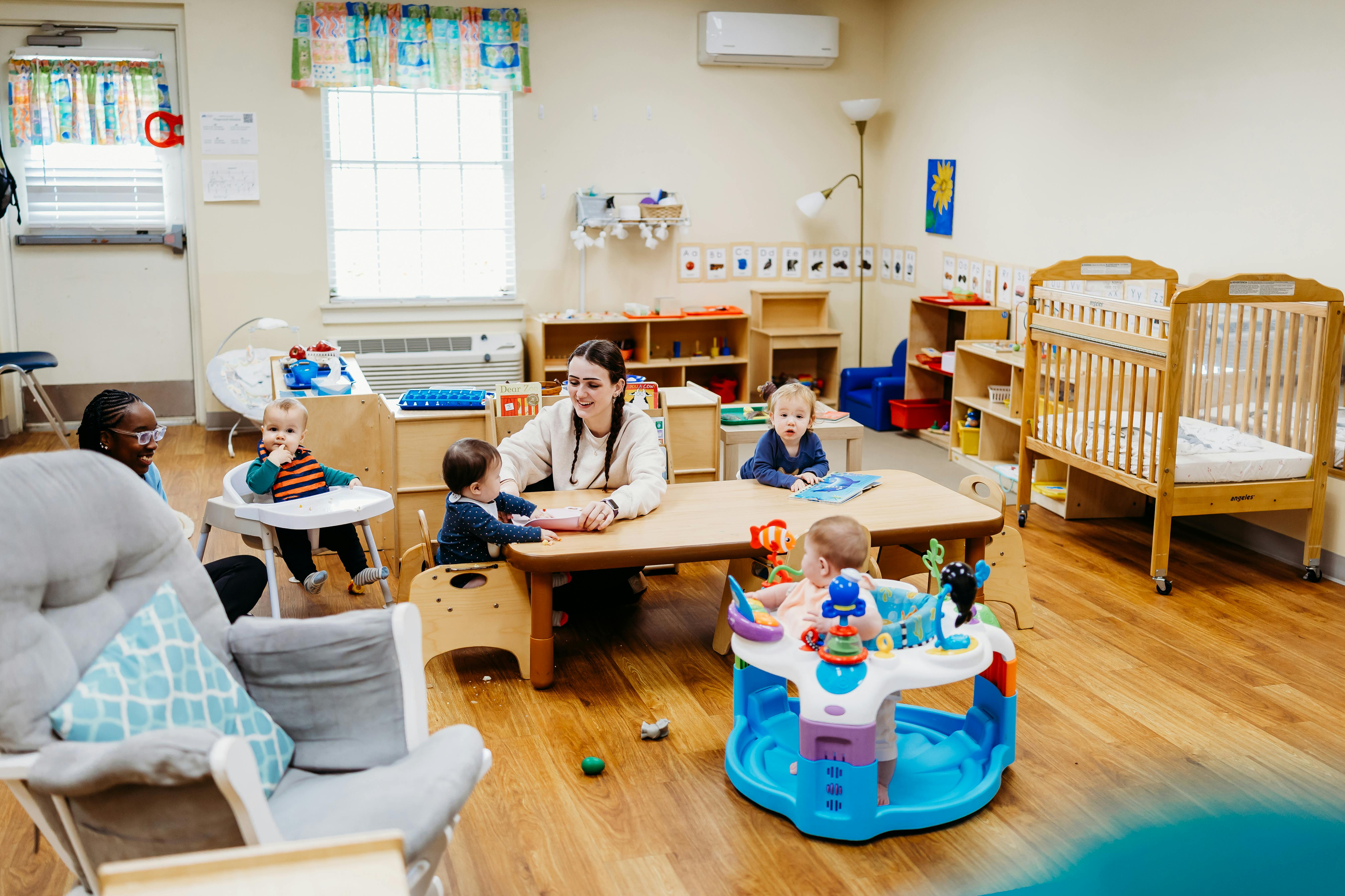 Children sitting at a table with adults in a classroom