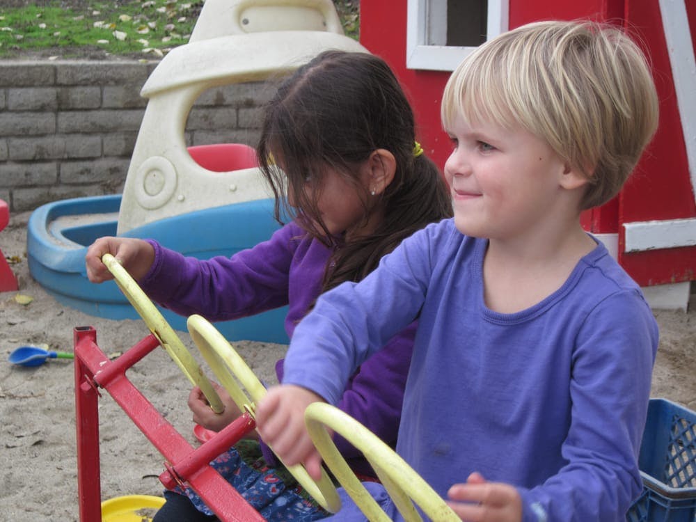 Two children playing on a seesaw in a sandbox