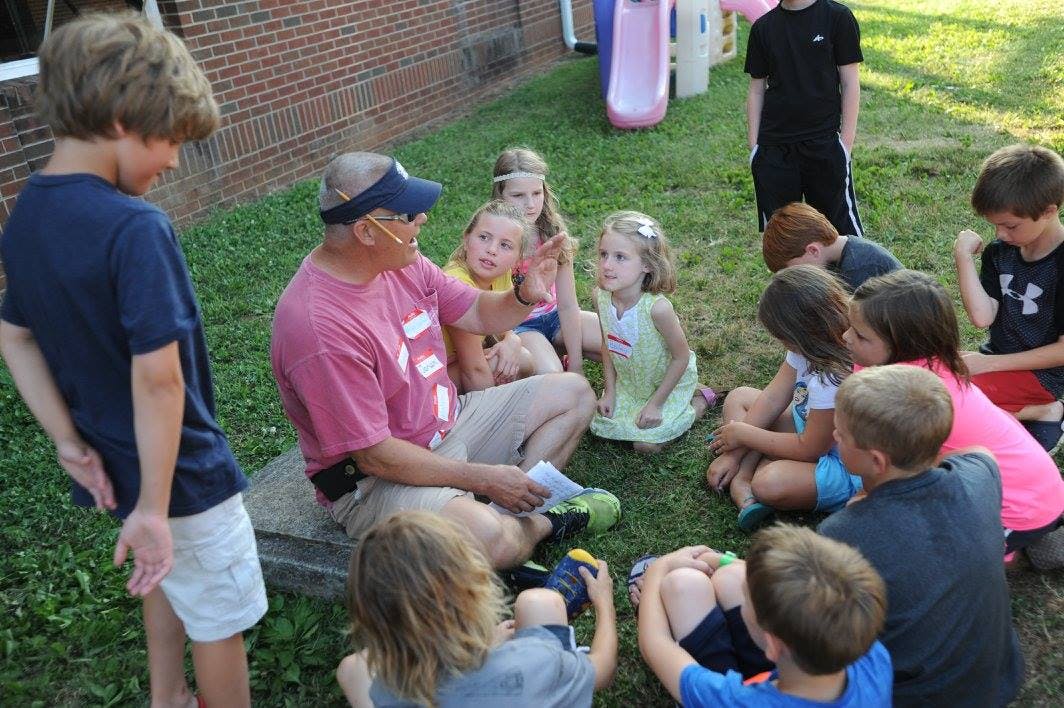 Adult person sitting on ground with children gathered around