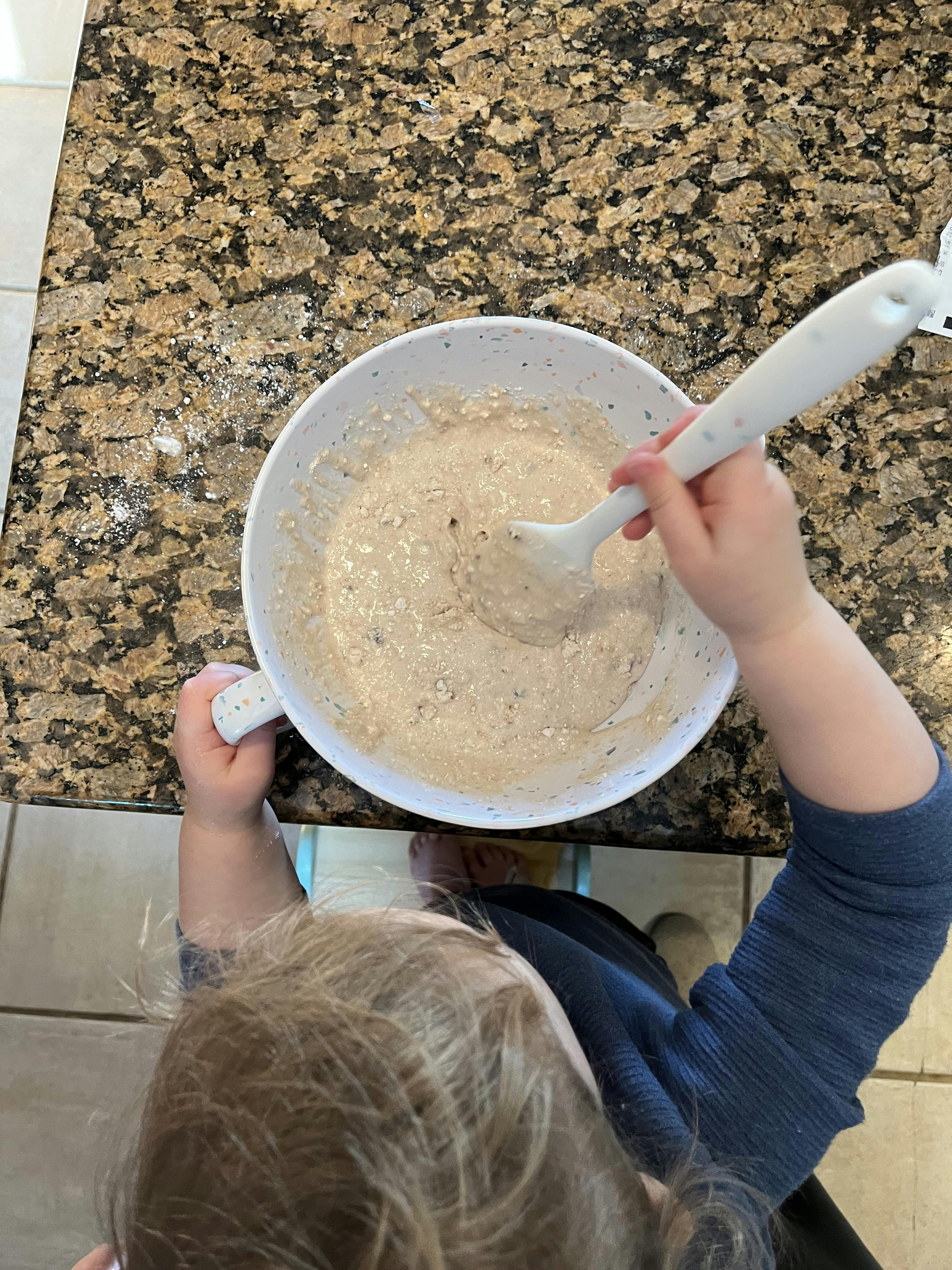Child stirring batter in a bowl with a spoon
