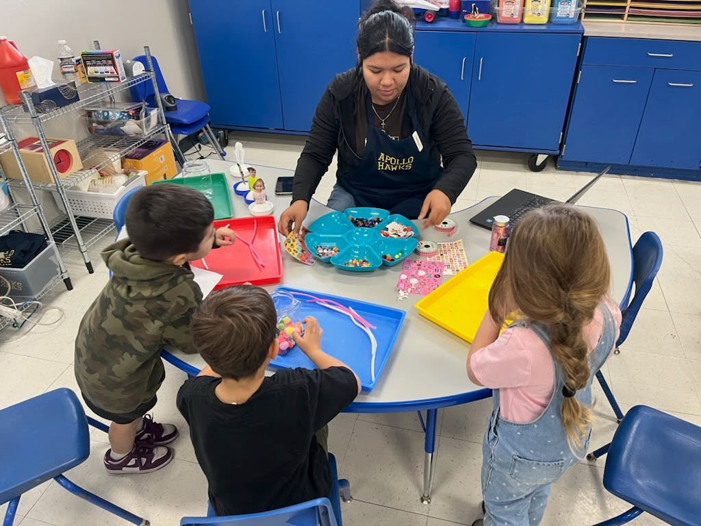 Person and three children doing crafts at a table