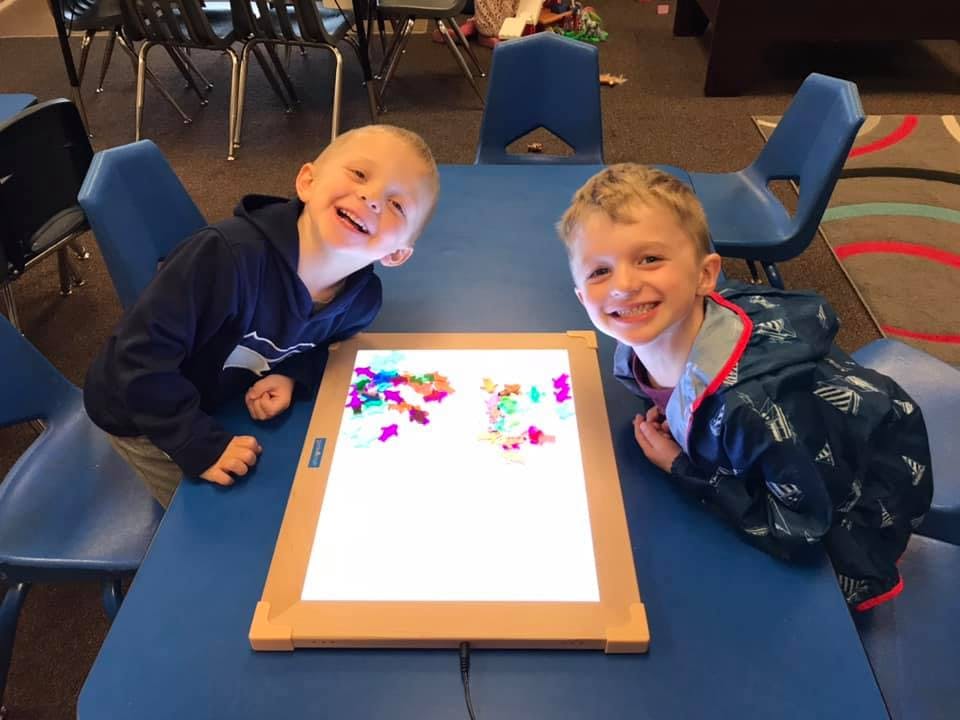 Two children looking at a light table with colorful shapes