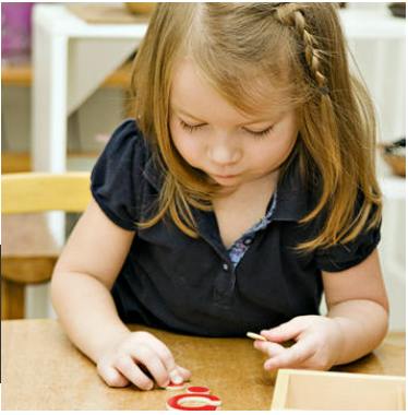 Child looking down at small objects on a table