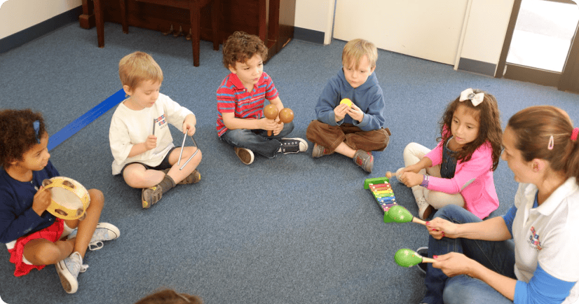 Adult and children sitting on floor with musical instruments