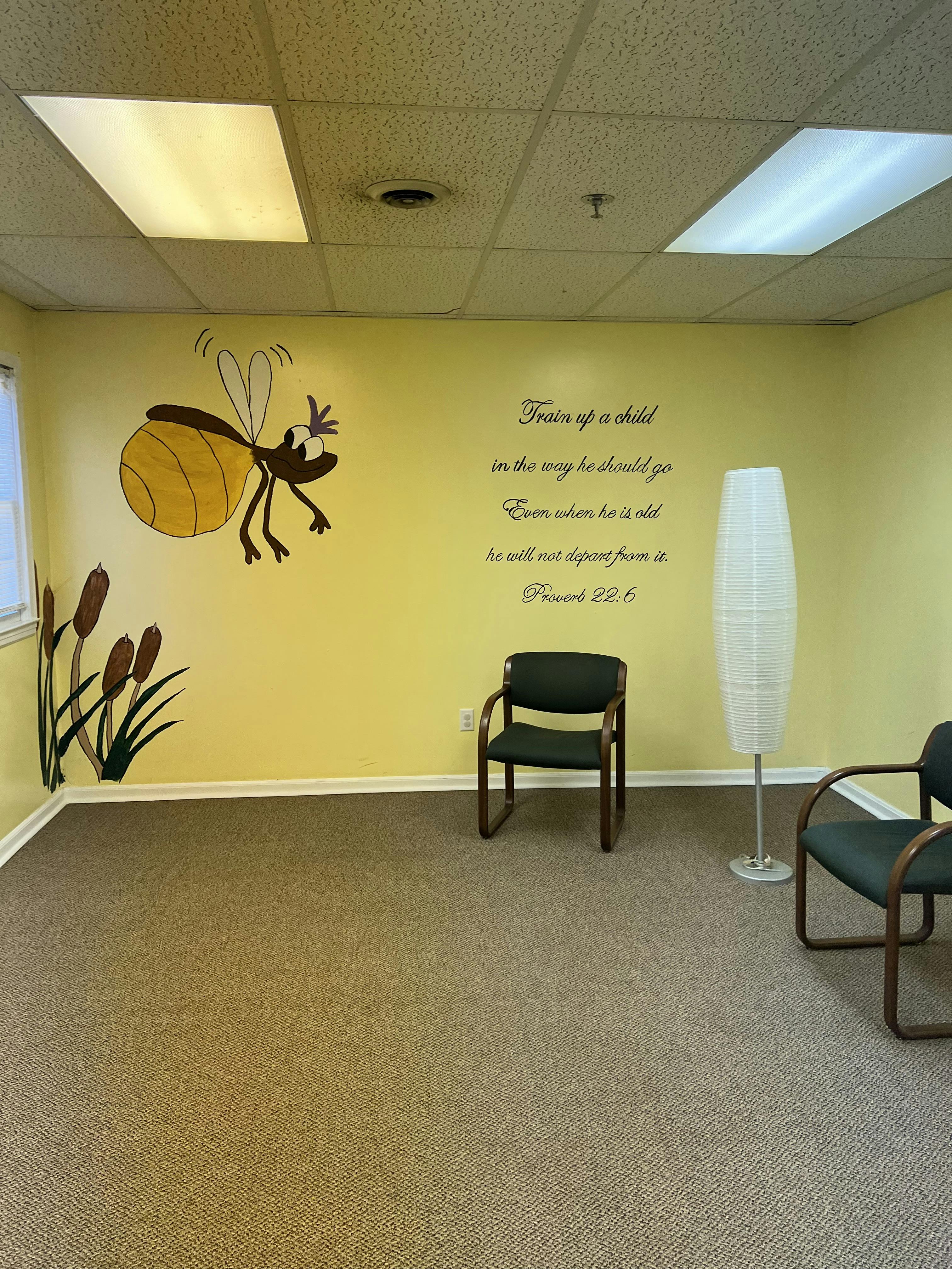 Room with yellow walls, bee and cattail wall decals, and chairs