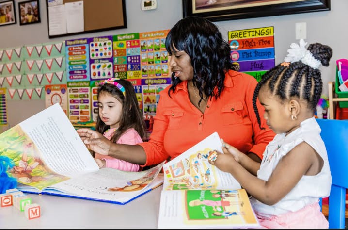 Person and two children reading books at a table