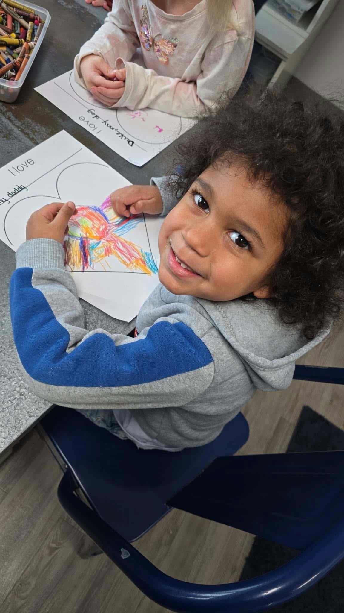 Child coloring a heart-shaped drawing at a table