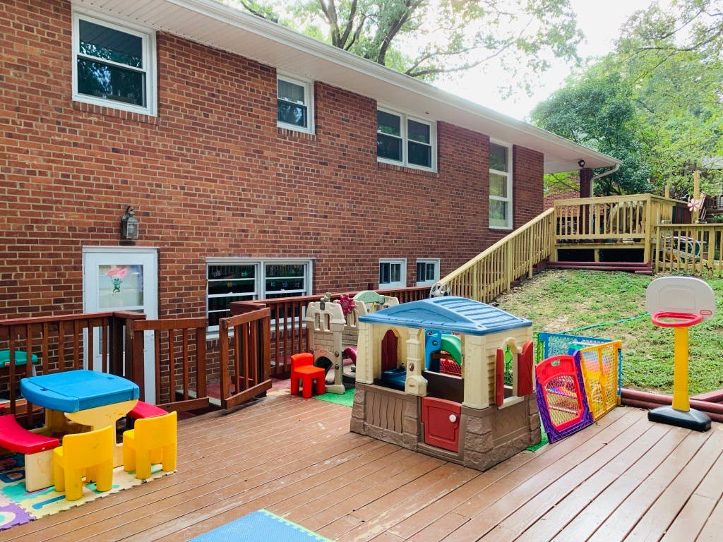Outdoor deck with children's playhouse, table, and basketball hoop