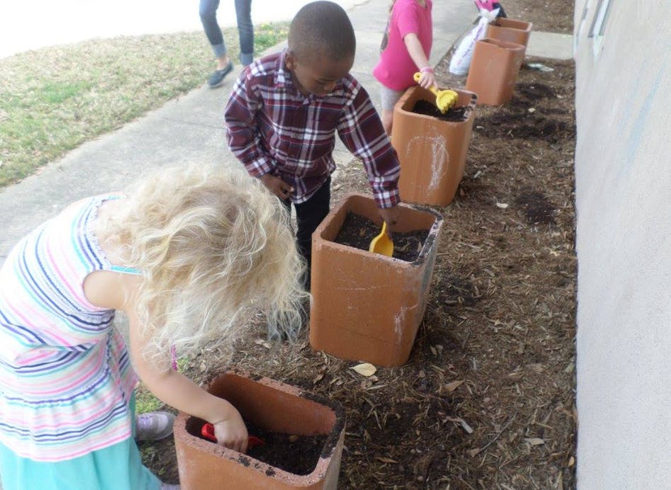 Children planting in pots outdoors