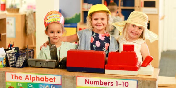 Three children playing with toy cash registers