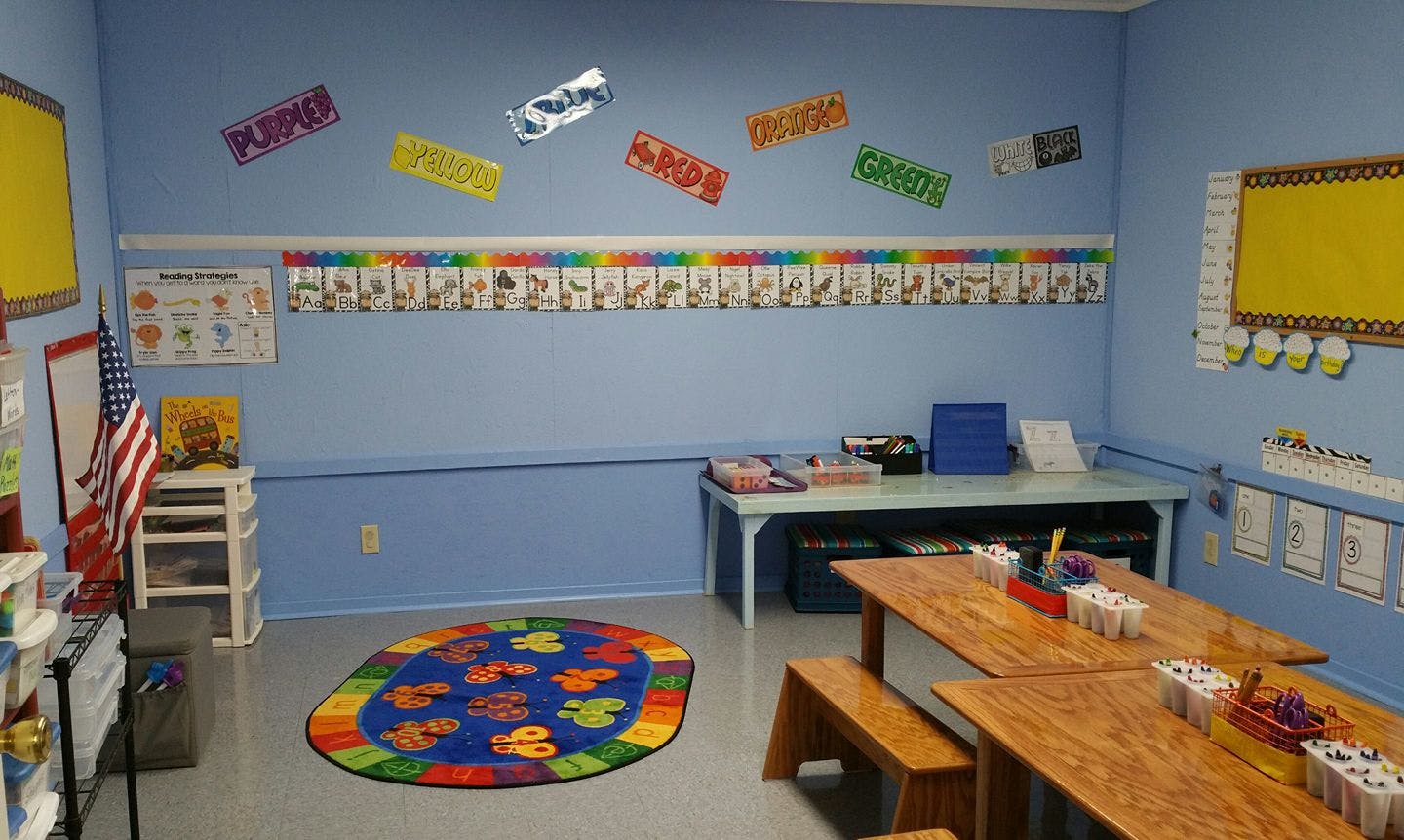 Classroom with tables, benches, and a colorful rug