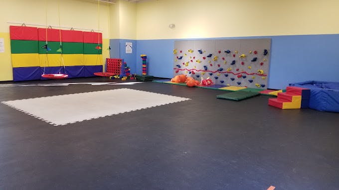 Indoor play area with climbing wall, swing, and soft mats