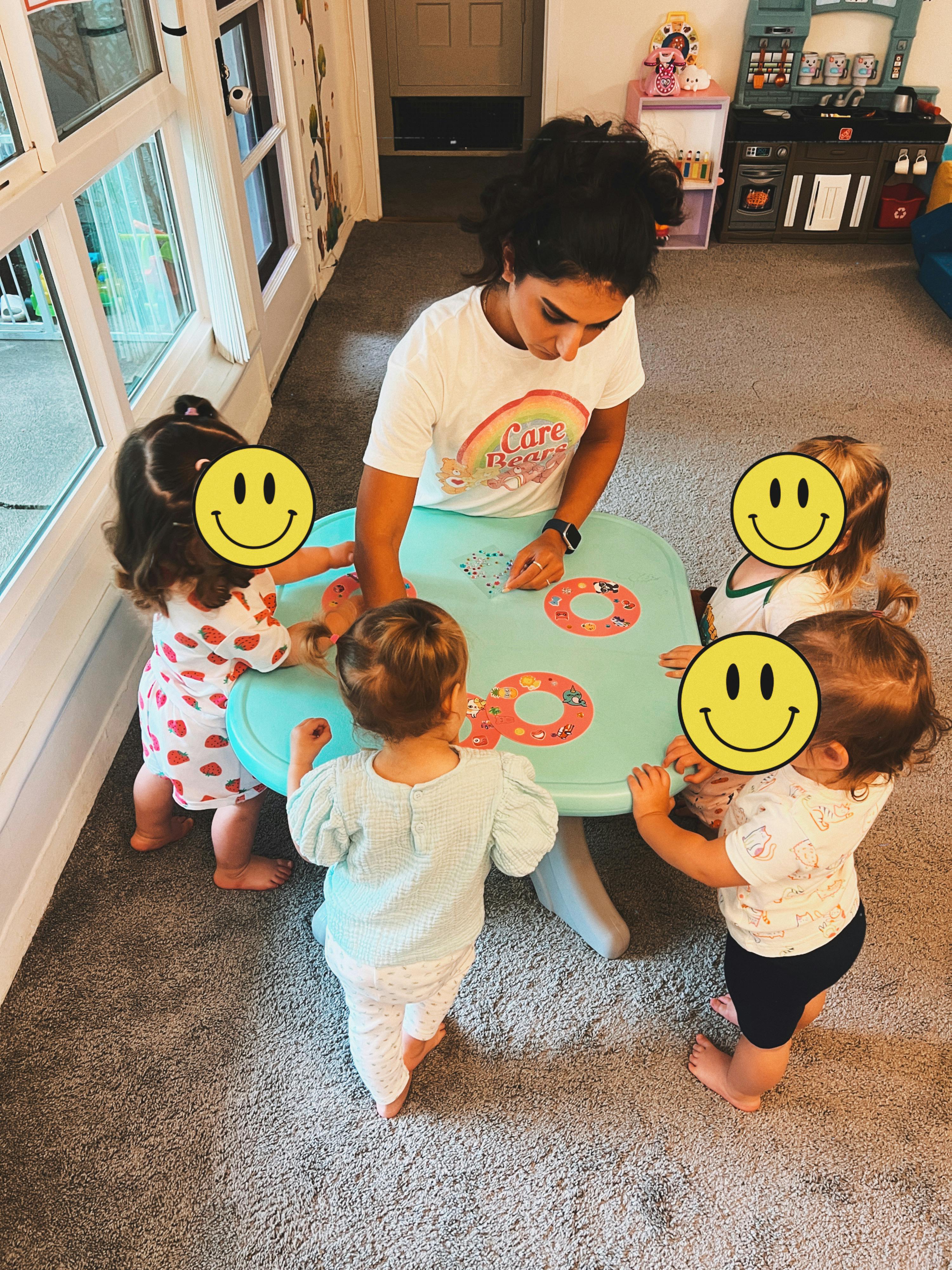 A person helping children with a craft project at a small table