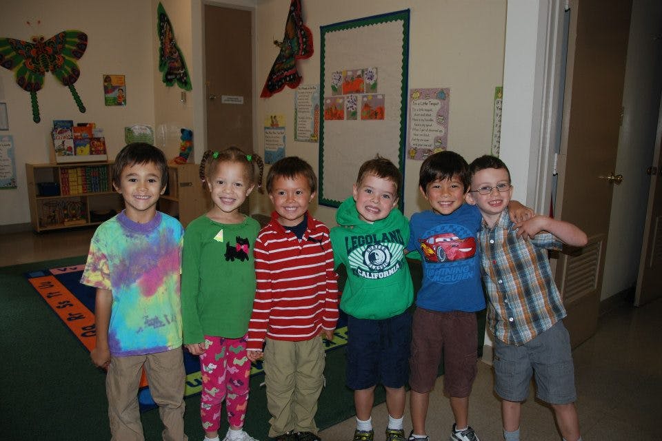 Six children standing together in a classroom