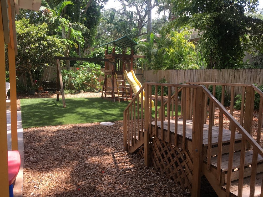 Wooden playground with slide and swing set in a grassy area