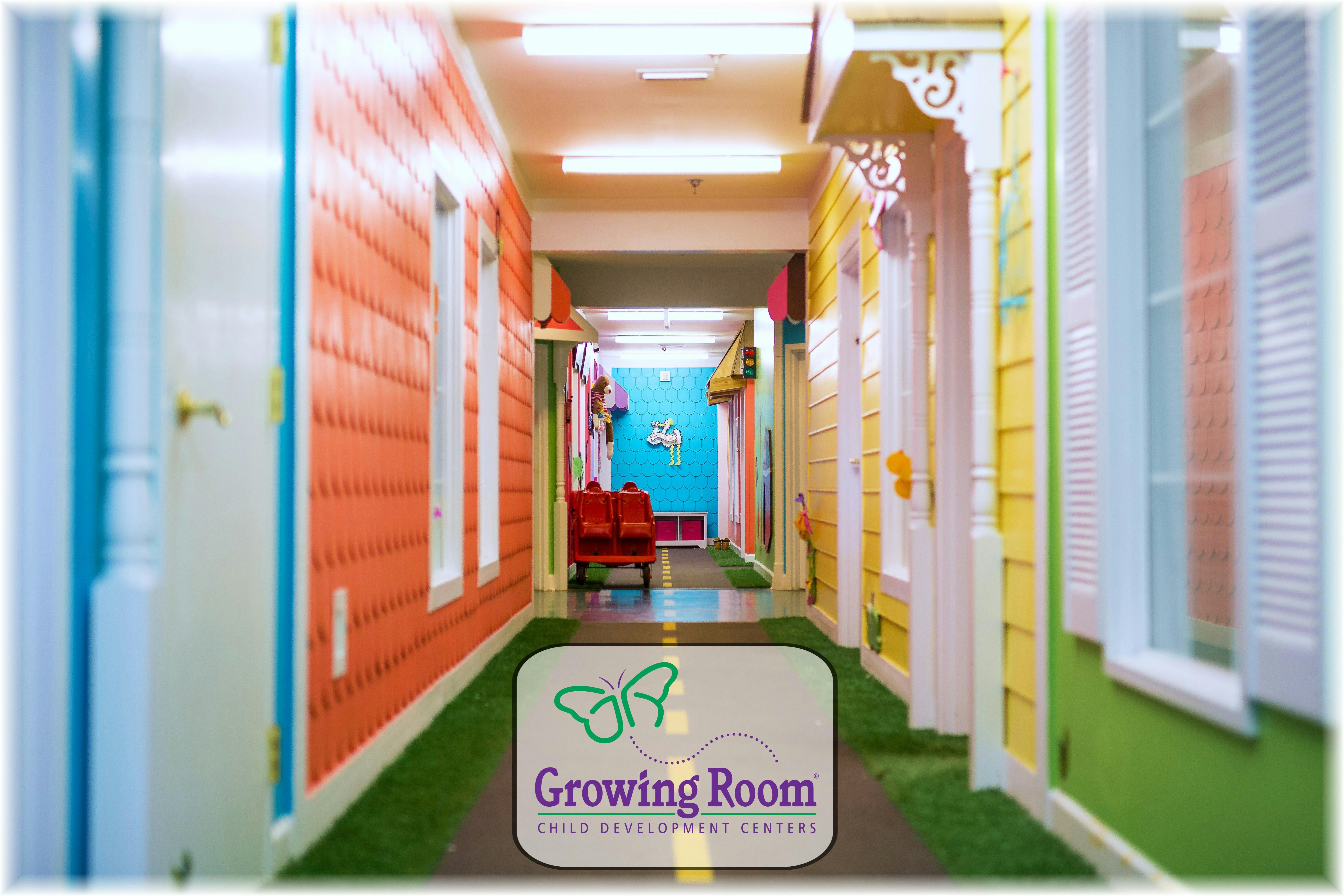 Hallway with colorful walls designed to look like houses, with a sign for "Growing Room"