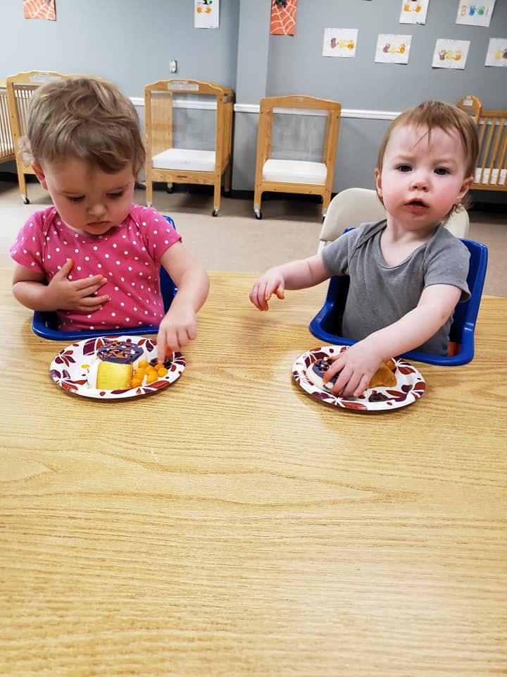 Two children sitting at a table with plates of food