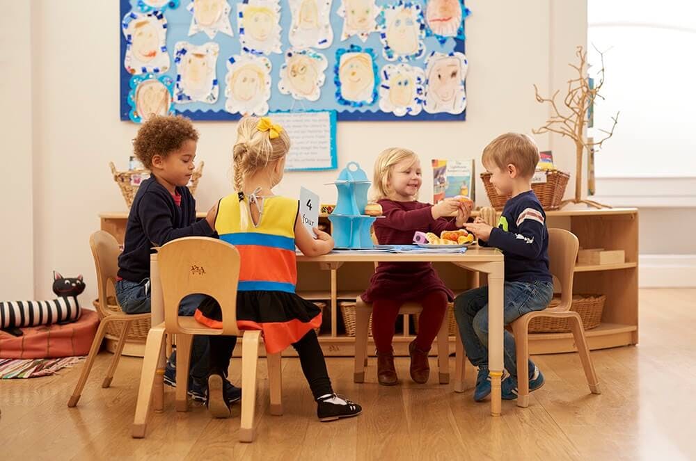 Four children sitting at a table in a classroom