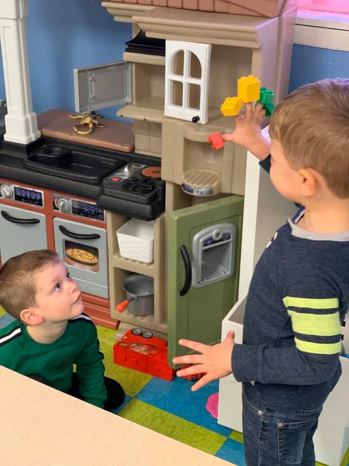 Two children playing with a toy kitchen set
