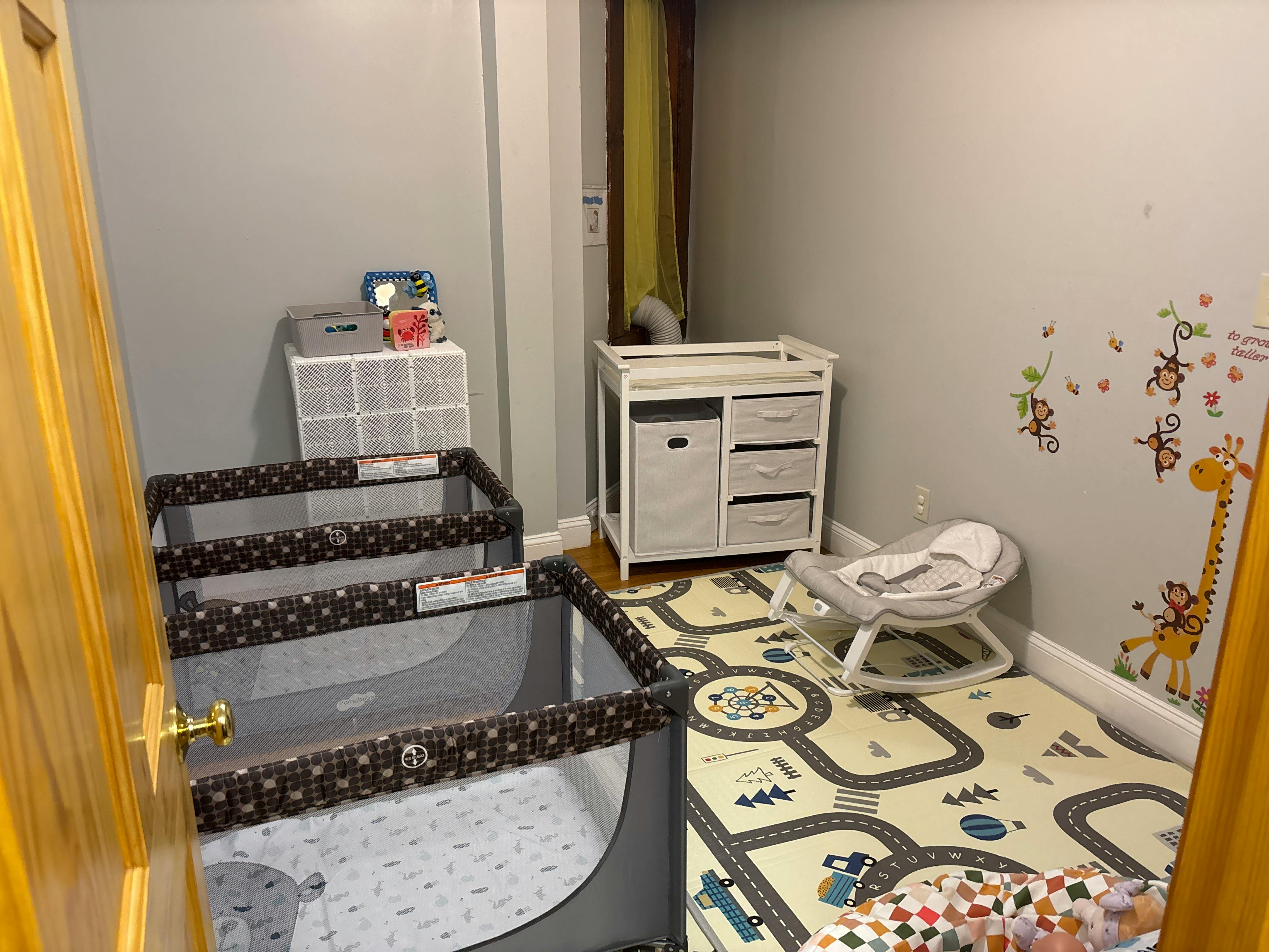 Nursery with two portable playards, a changing table, and a baby bouncer