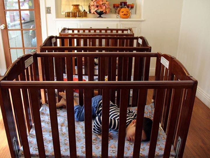 Child sleeping in a crib among several other cribs
