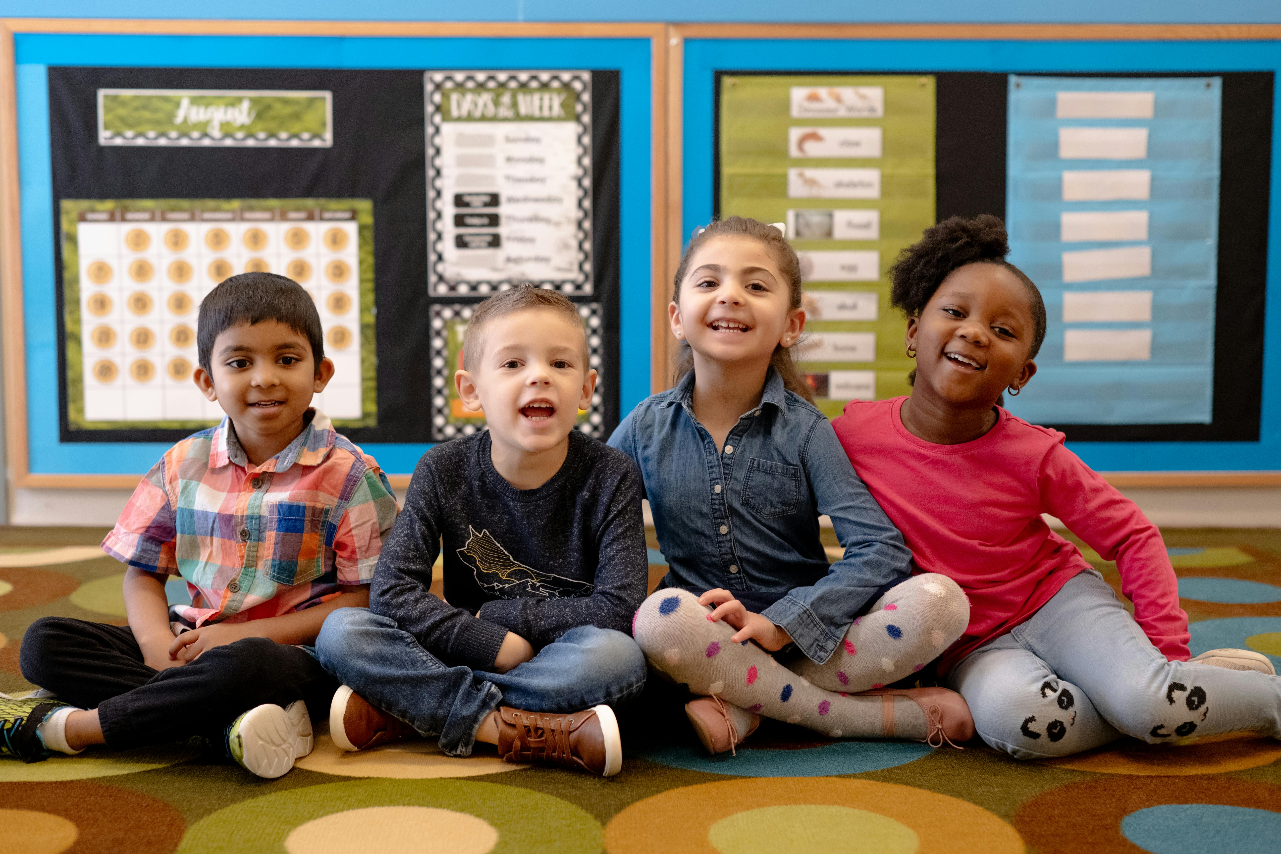 Four children sitting on the floor in a classroom