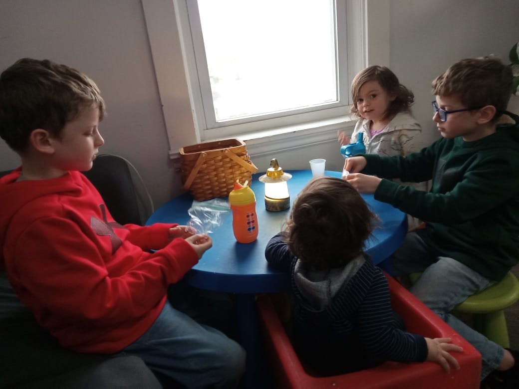 Four children sitting around a small blue table