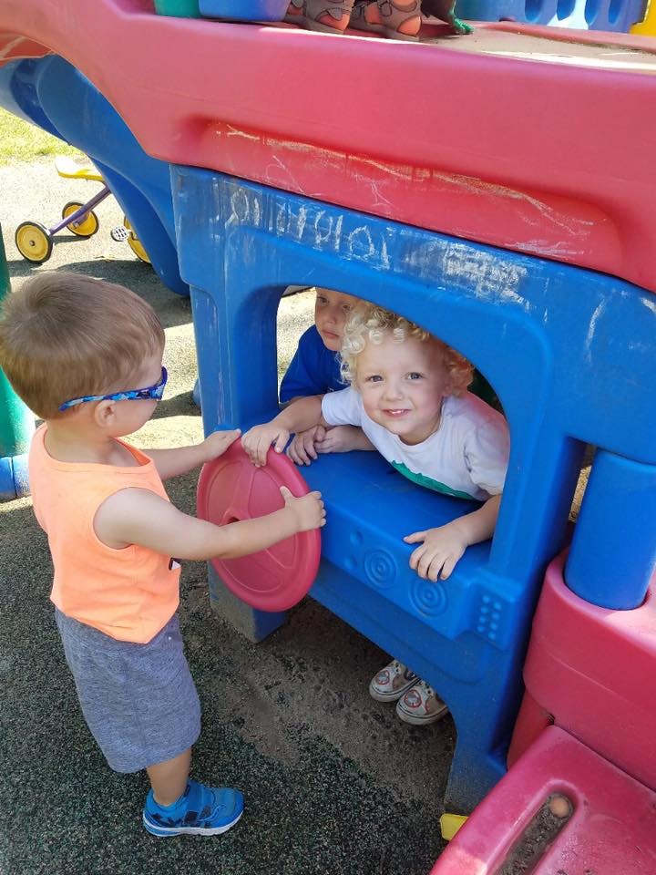 Two children playing on a colorful playground structure