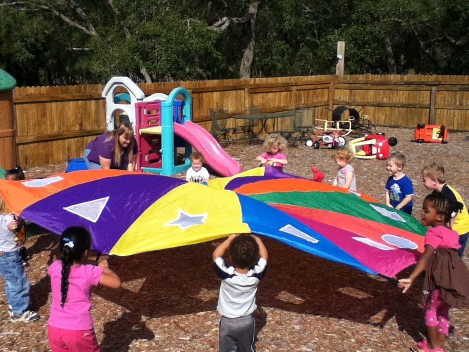 Adult and children playing with a colorful parachute outdoors