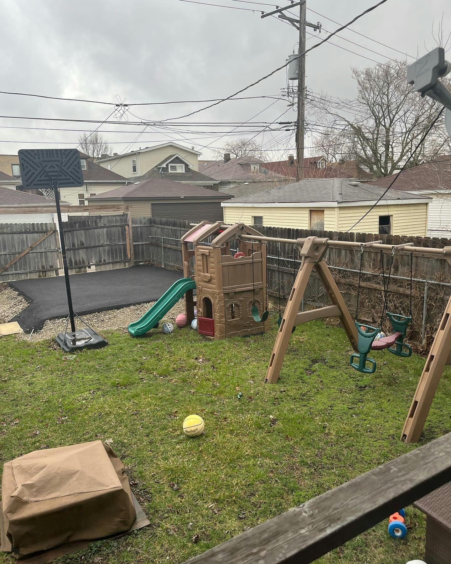 Backyard with a playset, swing set, and basketball hoop