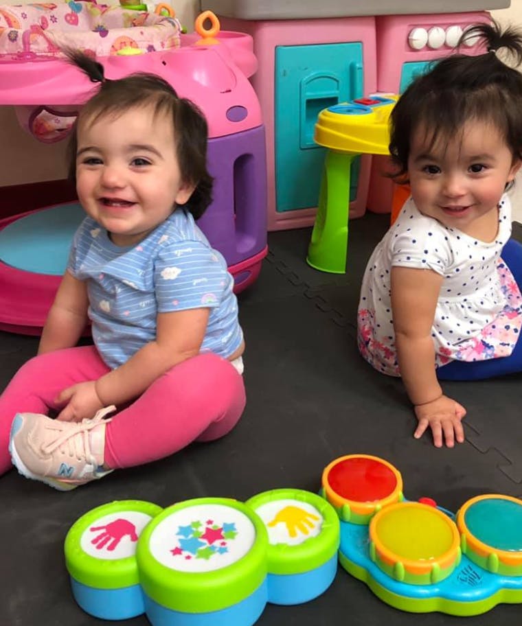 Two children sitting on the floor with toy drums